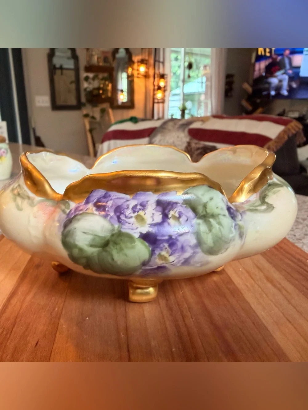 A hand-painted porcelain footed bowl with gilded rim and floral decoration.